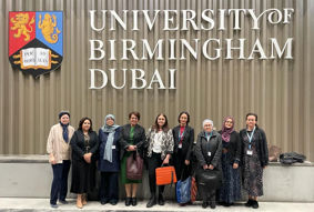 A group of people standing in a line in front of the University of Birmingham Dubai logo
