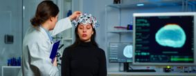 Woman adjusting an EEG device being worn by a female patient
