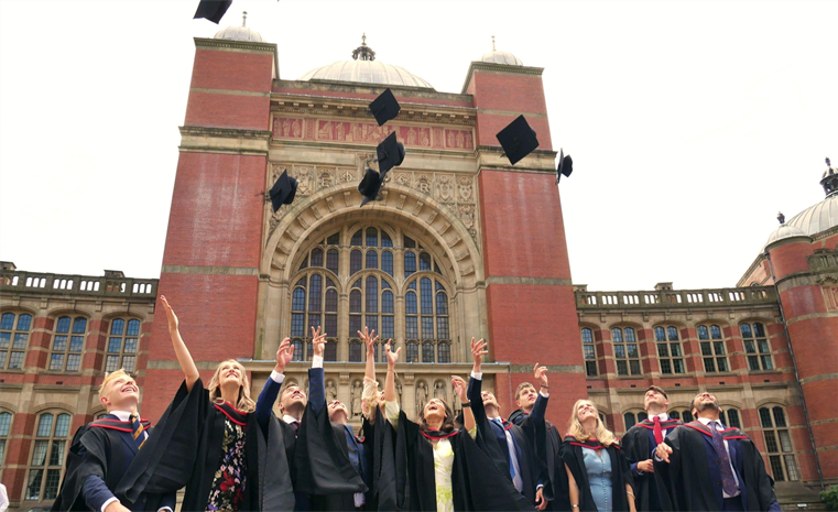A group of University of Birmingham graduates throwing their graduation caps in the air