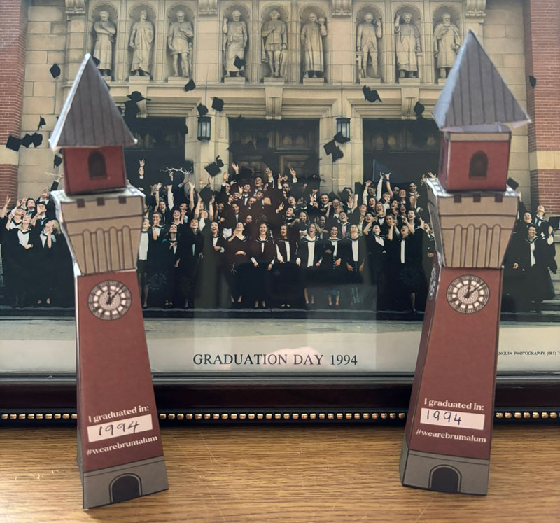 Paper models of Old Joes in front of a 1994 photo of graduation