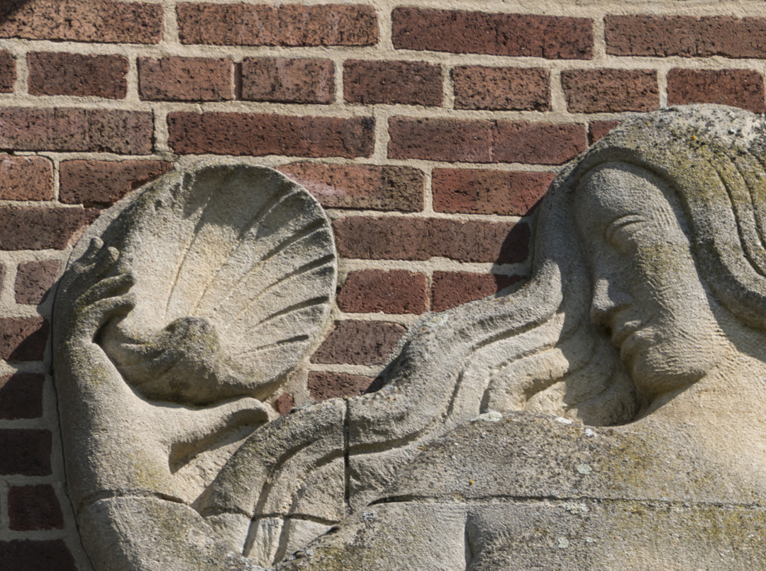 Close up detail of stone carved Mermaid Relief by William Bloye including face and left hand holding shell