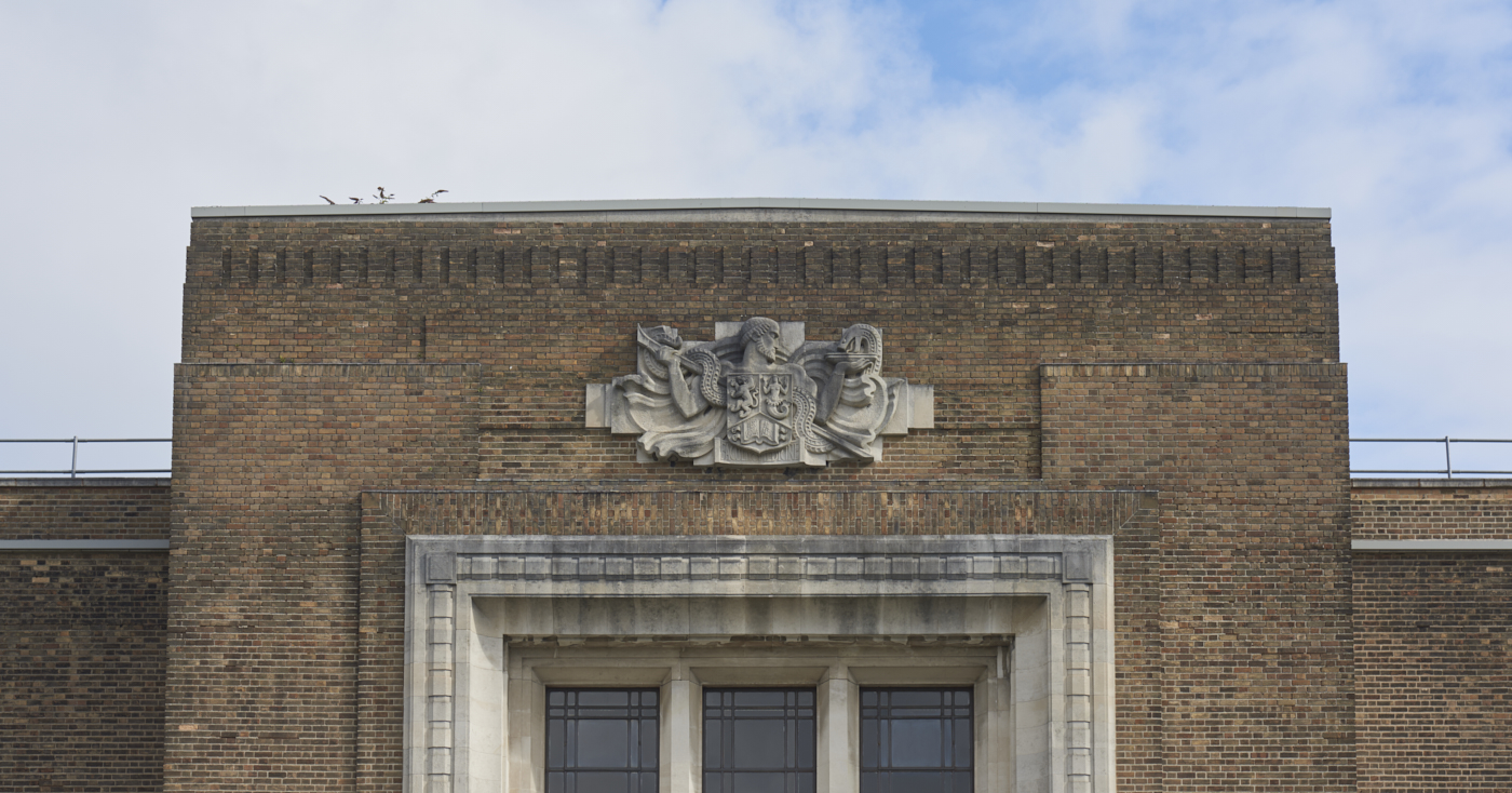 Carved stone shield featuring a male figure and a serpent by William Bloye in context of the Medical School Building