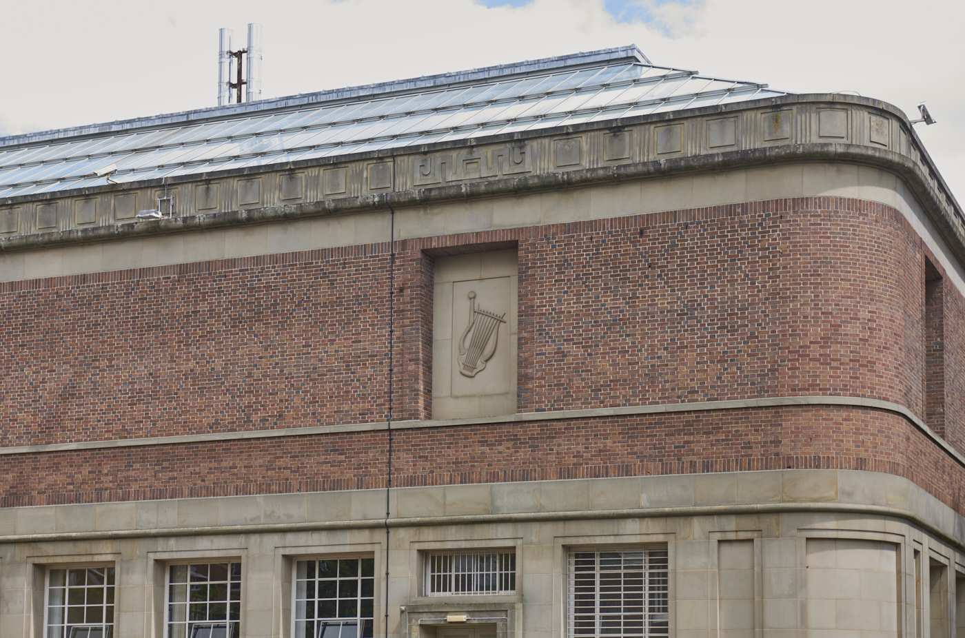 Carved stone panel set into the wall of the Barber Institute of Fine Arts by Gordon Herickx featuring a carving of a lyre in context of building