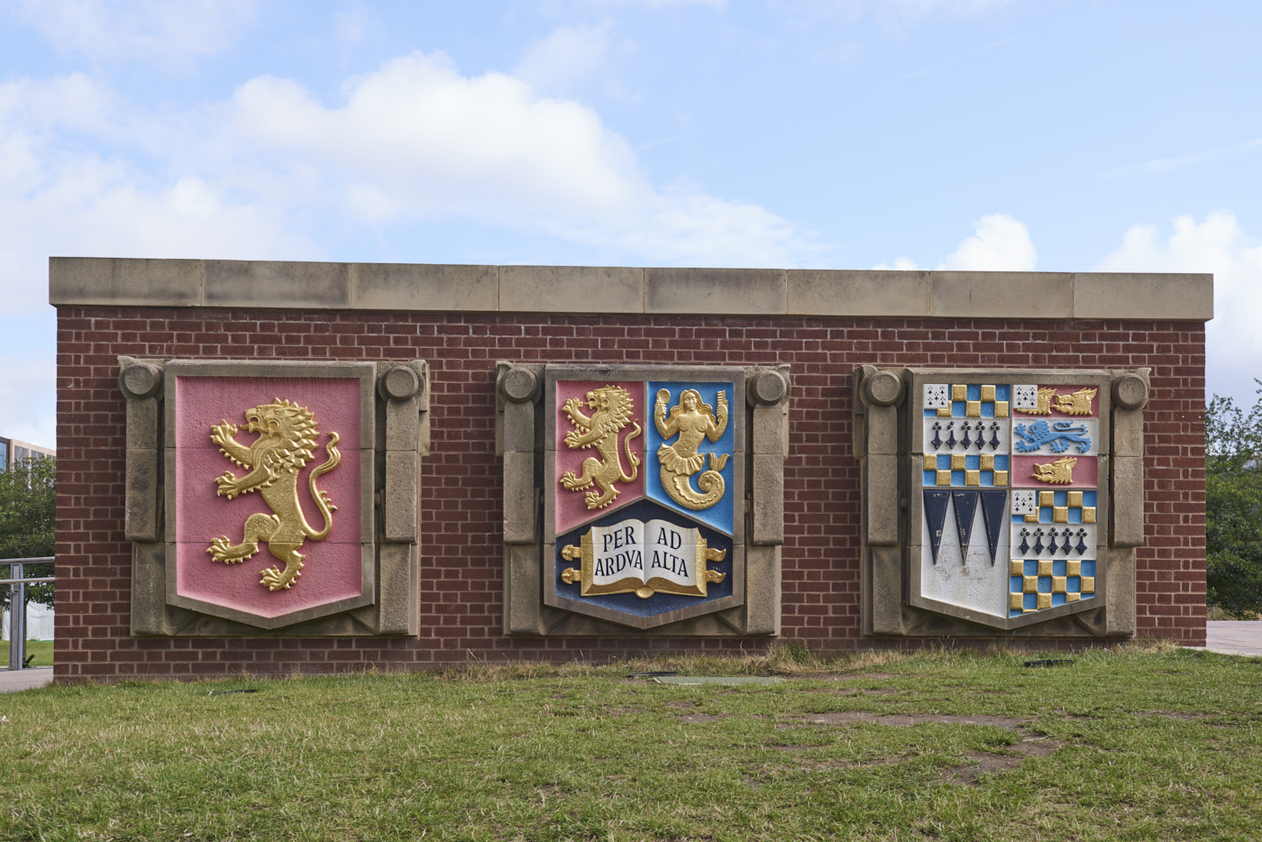 Set of three carved and painted stone Heraldic Shields from Old Library by William Bloye set into wall