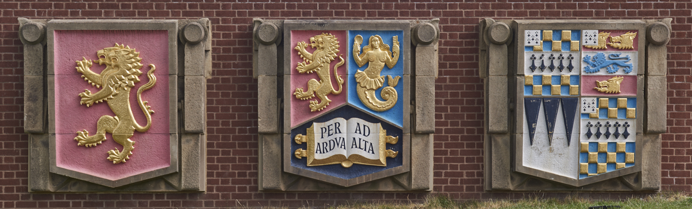 Set of three carved and painted stone Heraldic Shields from Old Library by William Bloye set into wall