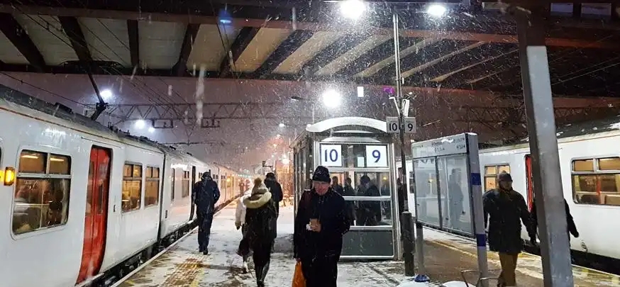 Falling snow on  train carriages and people