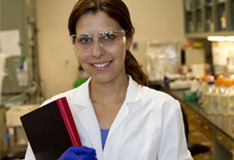 Female lab scientist holding a textbook within a laboratory