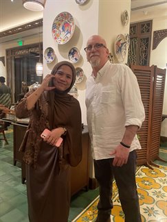 A woman wearing a headscarf (left) and a man (right) smiling at the camera.