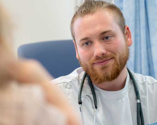 Male nursing student speaking to patient which is out of shot