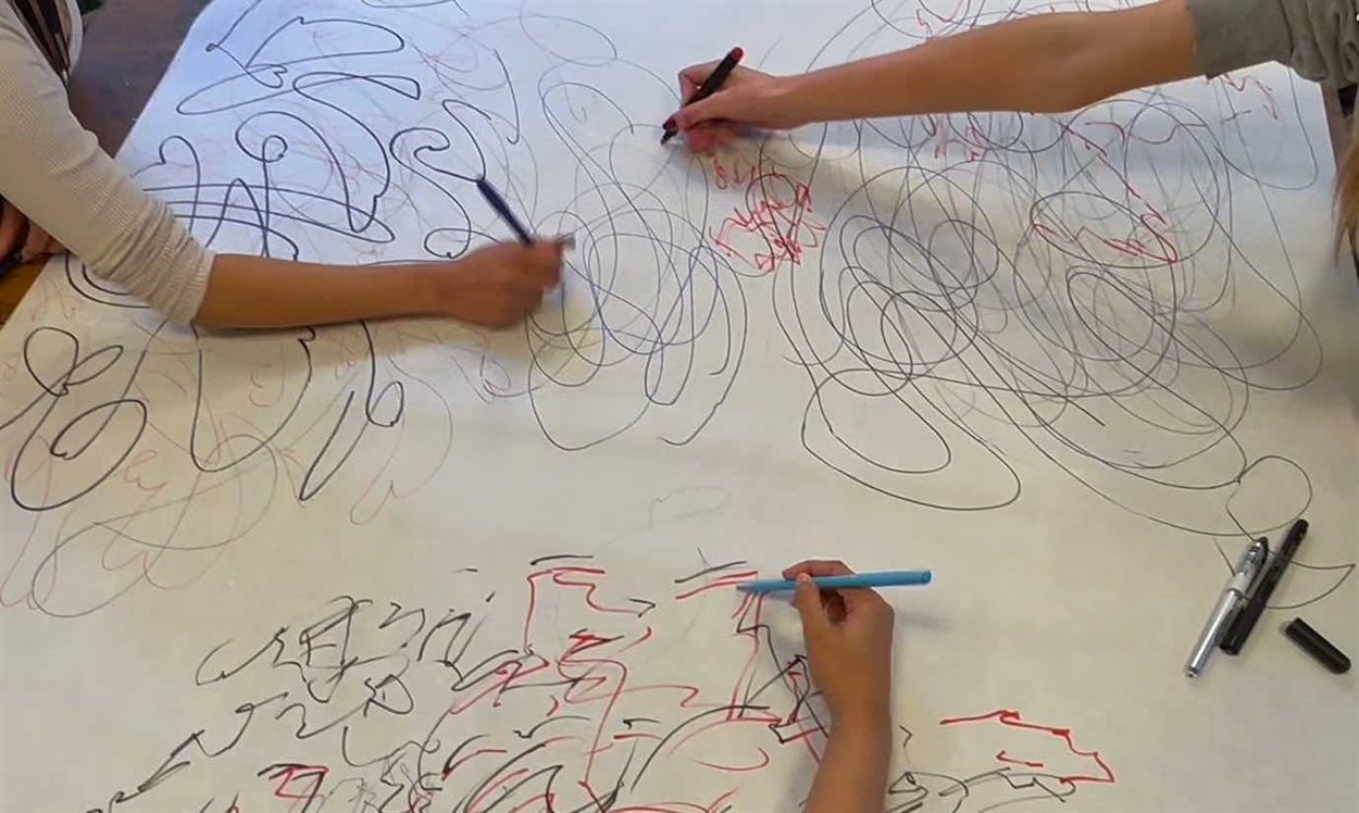 People drawing rhythms and lines on large paper