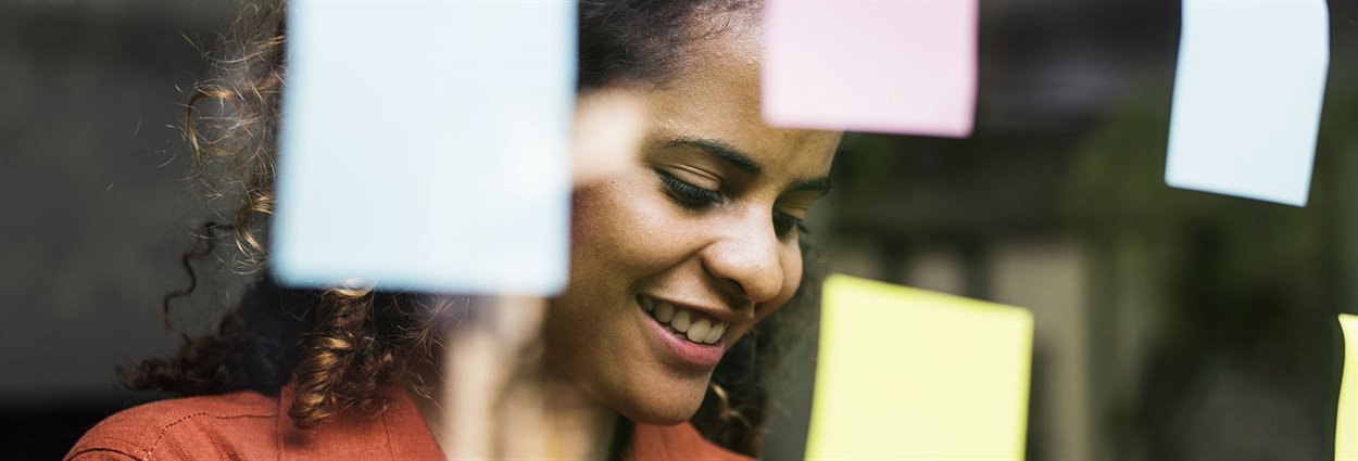 Woman looking at post-stick notes on glass board