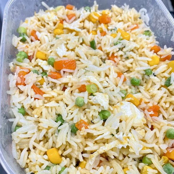 A Tupperware container filled with colourful egg and vegetable fried rice