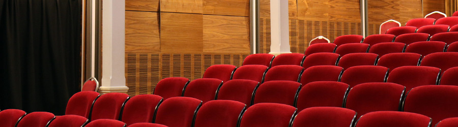 An auditorium with red chairs.