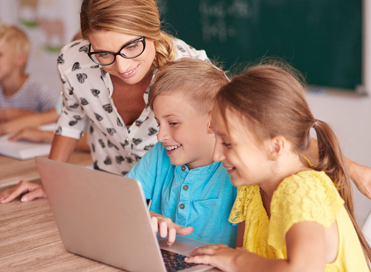 Teacher working on a laptop with children