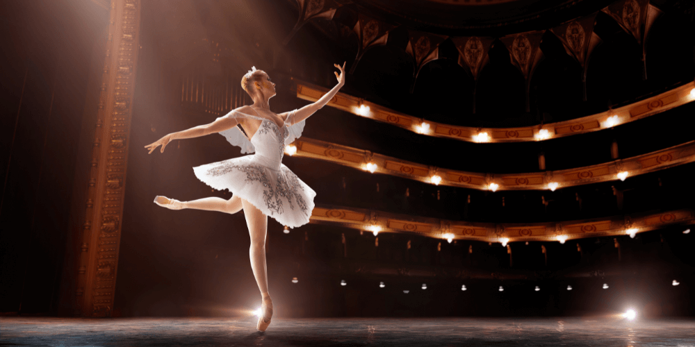 A ballerina en pointe on stage in a large theatre