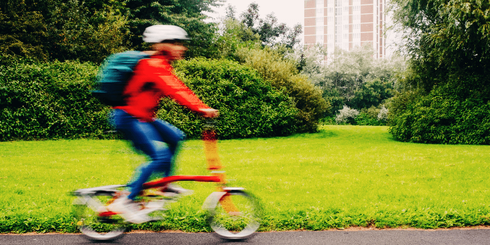A person riding a folding bike surrounded by greenery
