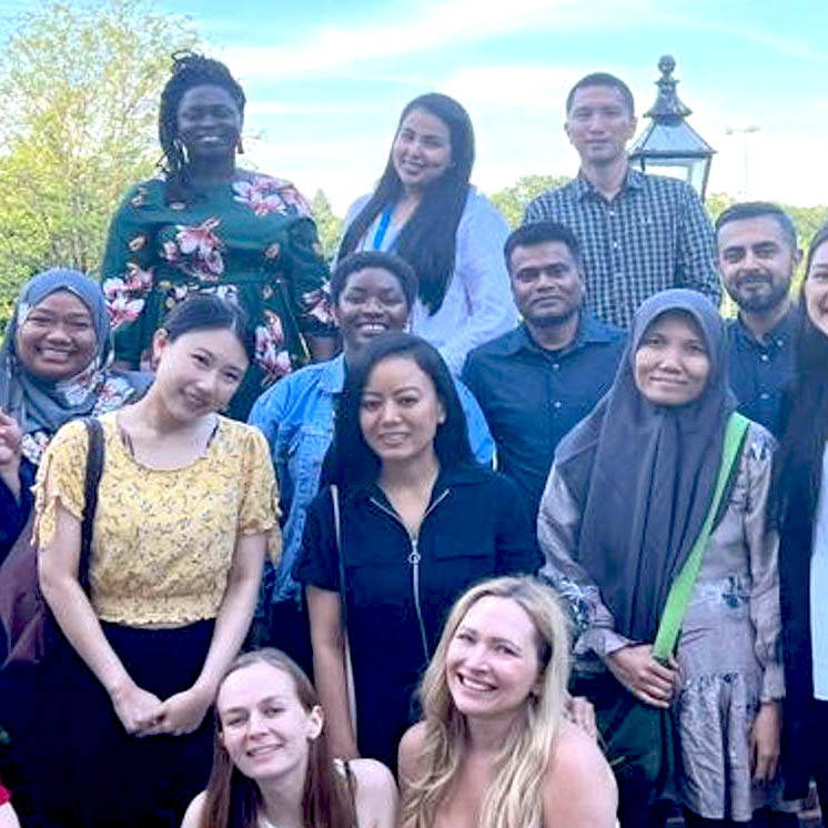 Postgraduate students grouped together for a photo in a sunny garden