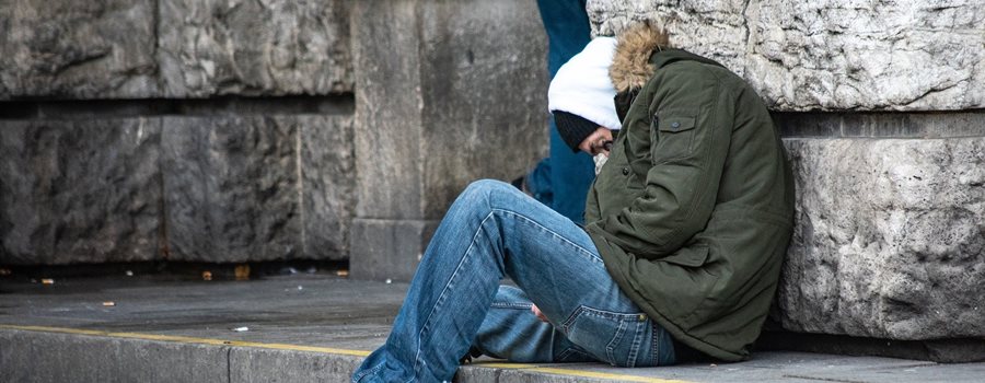 Homeless man sat on a set of steps asleep