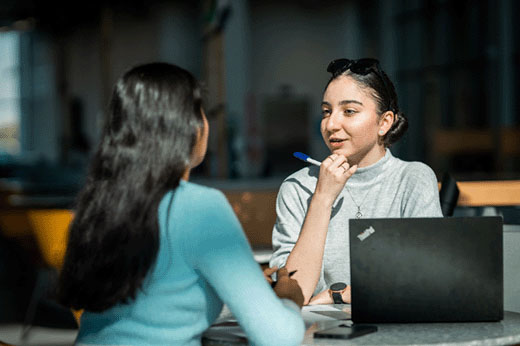 two female students sitting at a table having a discussion