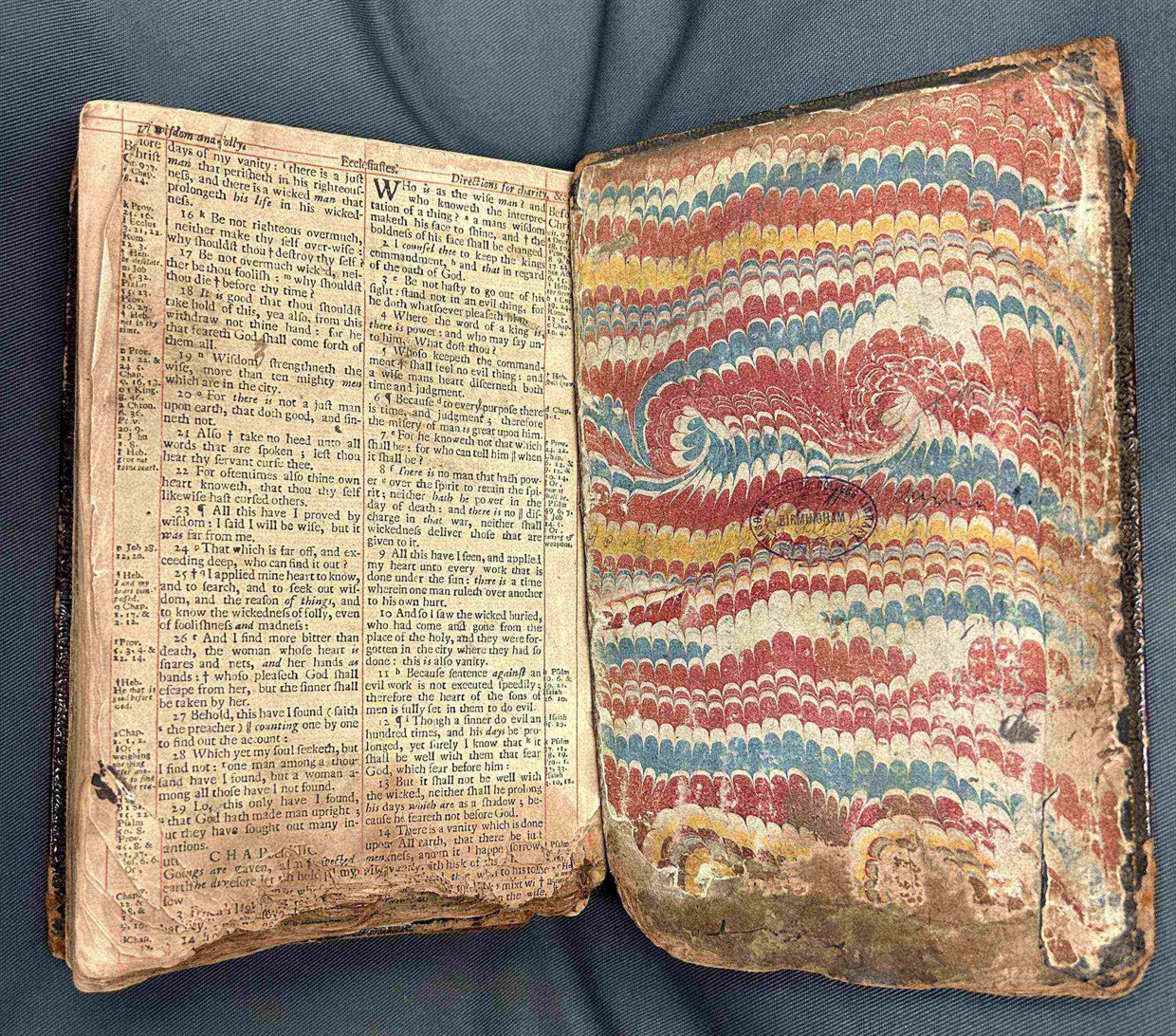 An old Bible, opened to show its marbled inside back cover. The bottom edge is scorched from the fires during the riots.