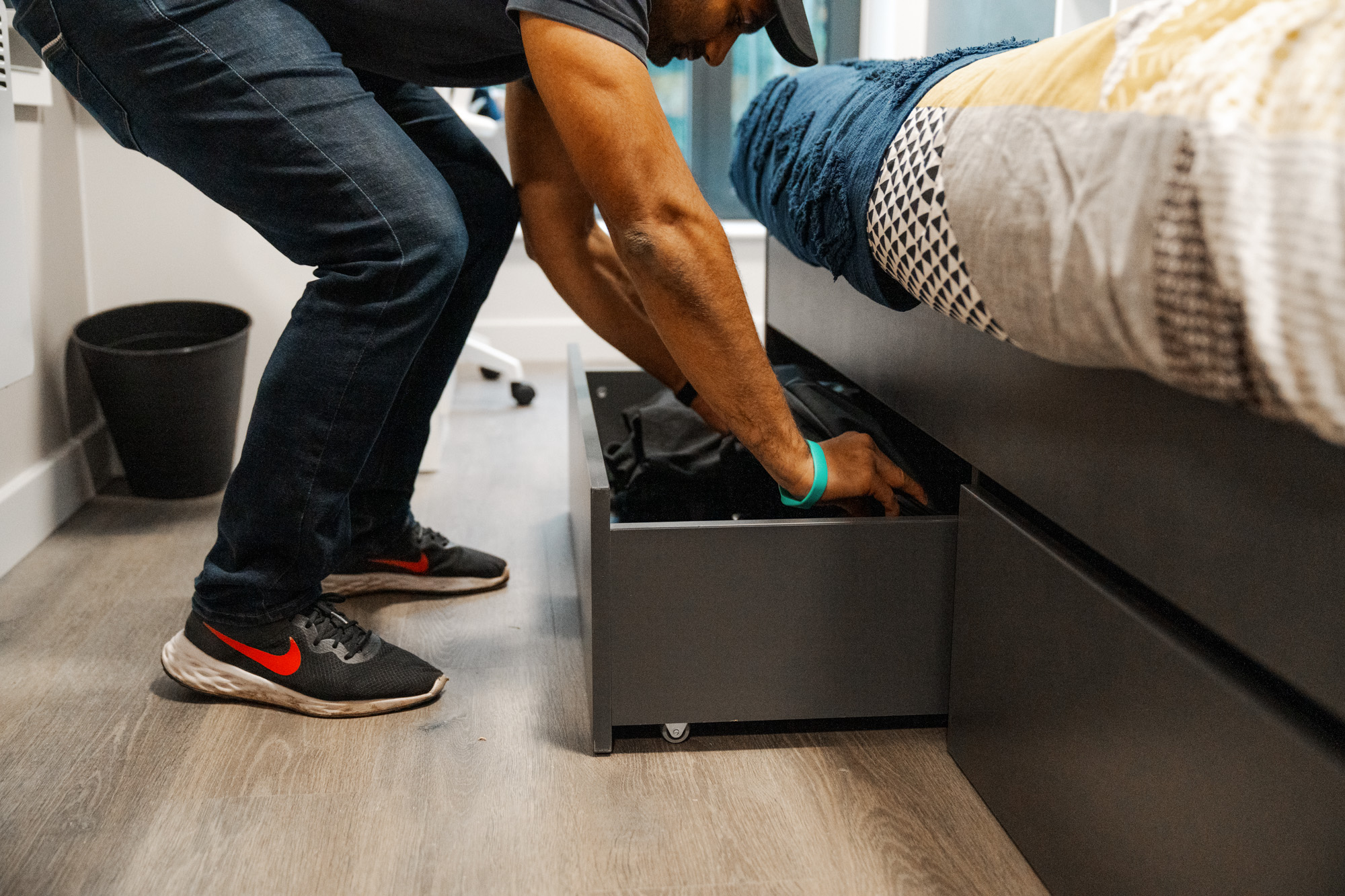 A student opening the draws underneath his bed.