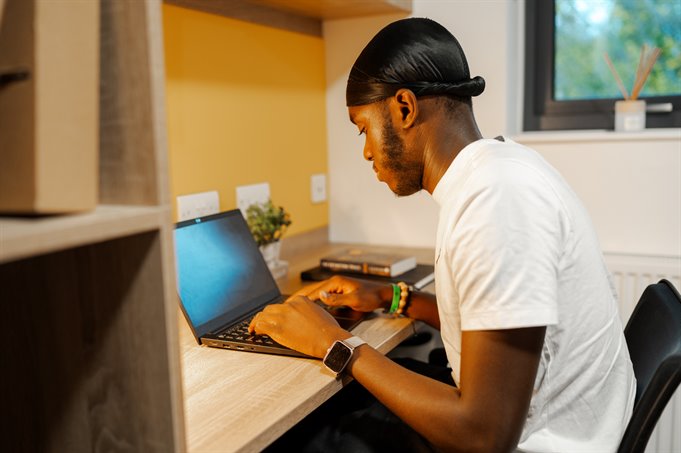 Student sat at his desk on his laptop