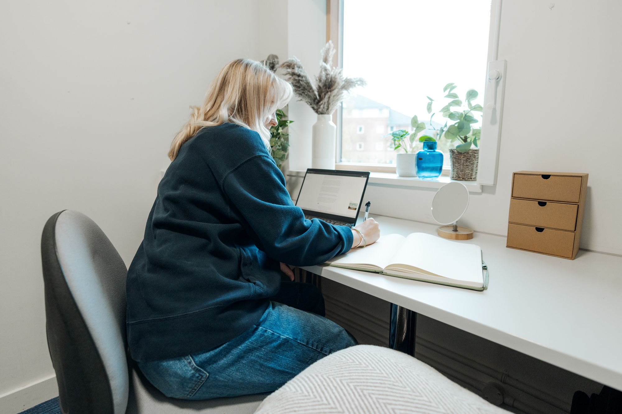 Student on her laptop and writing on a notepad