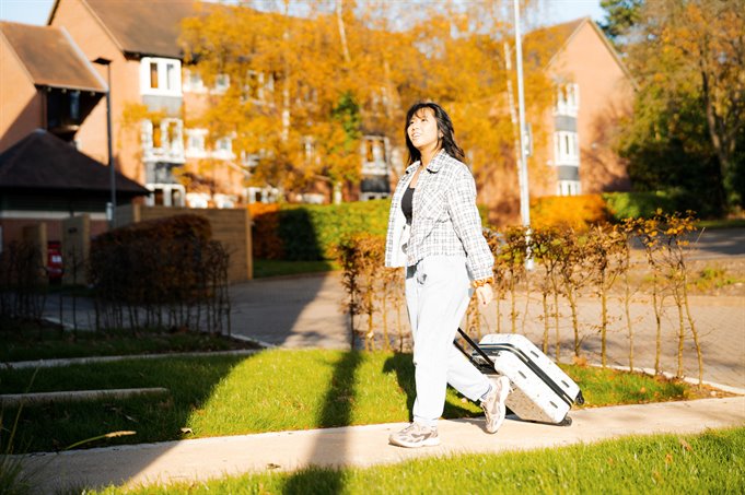 Student pulling her suitcase into her accommodation.