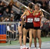 A team of female athletics runners have just finished a race and are hugging each other in celebration