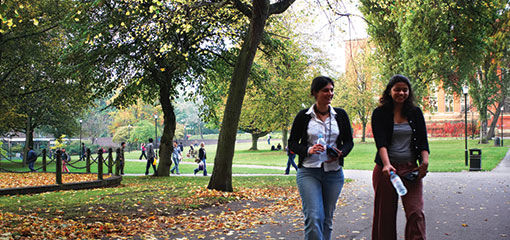 Photograph of two students walking across the green University of Birmingham campus