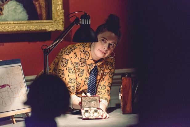 A woman in a leopard printed shirt holds a vintage trinket case under a desk lamp.