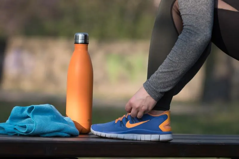 Athlete tying a shoe next to a water bottle