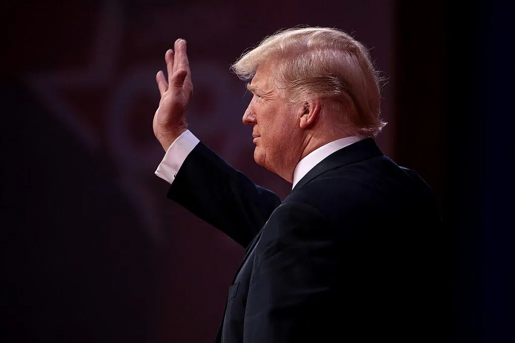 Donald Trump waving at a crowd (facing the left). 