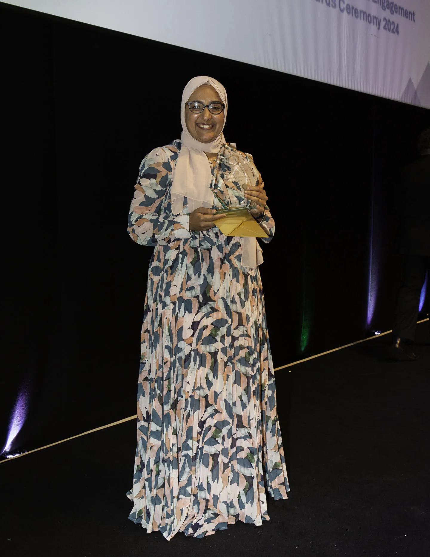 Dr Hanan Fara on stage holding her award.