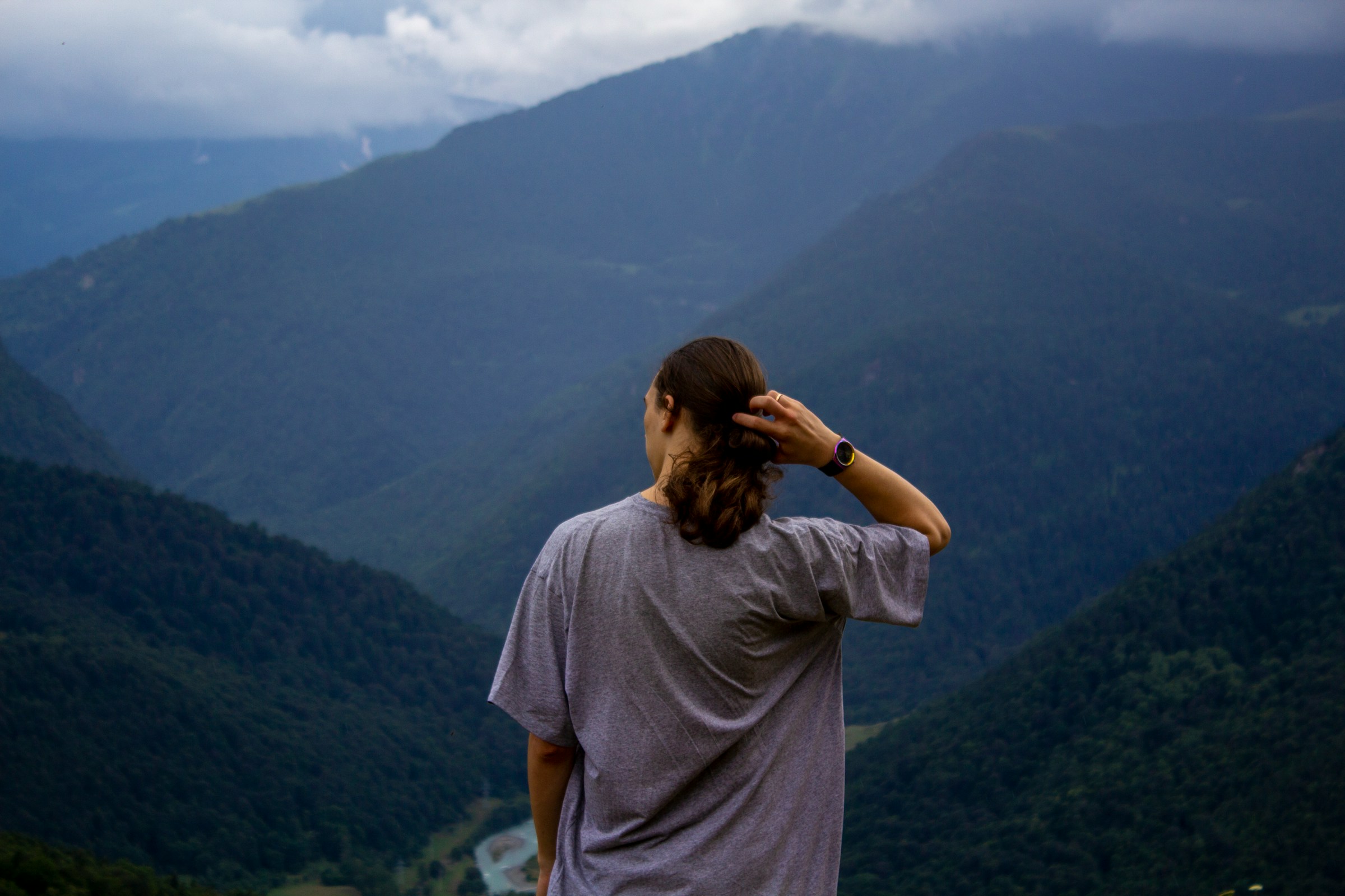 Young man gazing over woodland and mountains