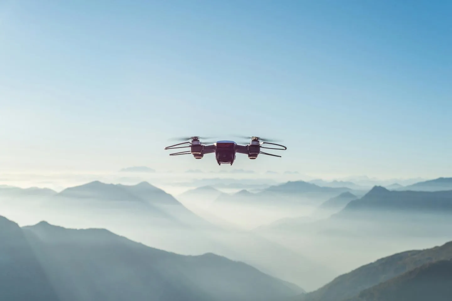 A drone hovers above mist-shrouded mountains