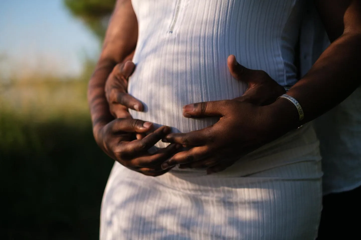 A pregnant person, with hands on belly. 