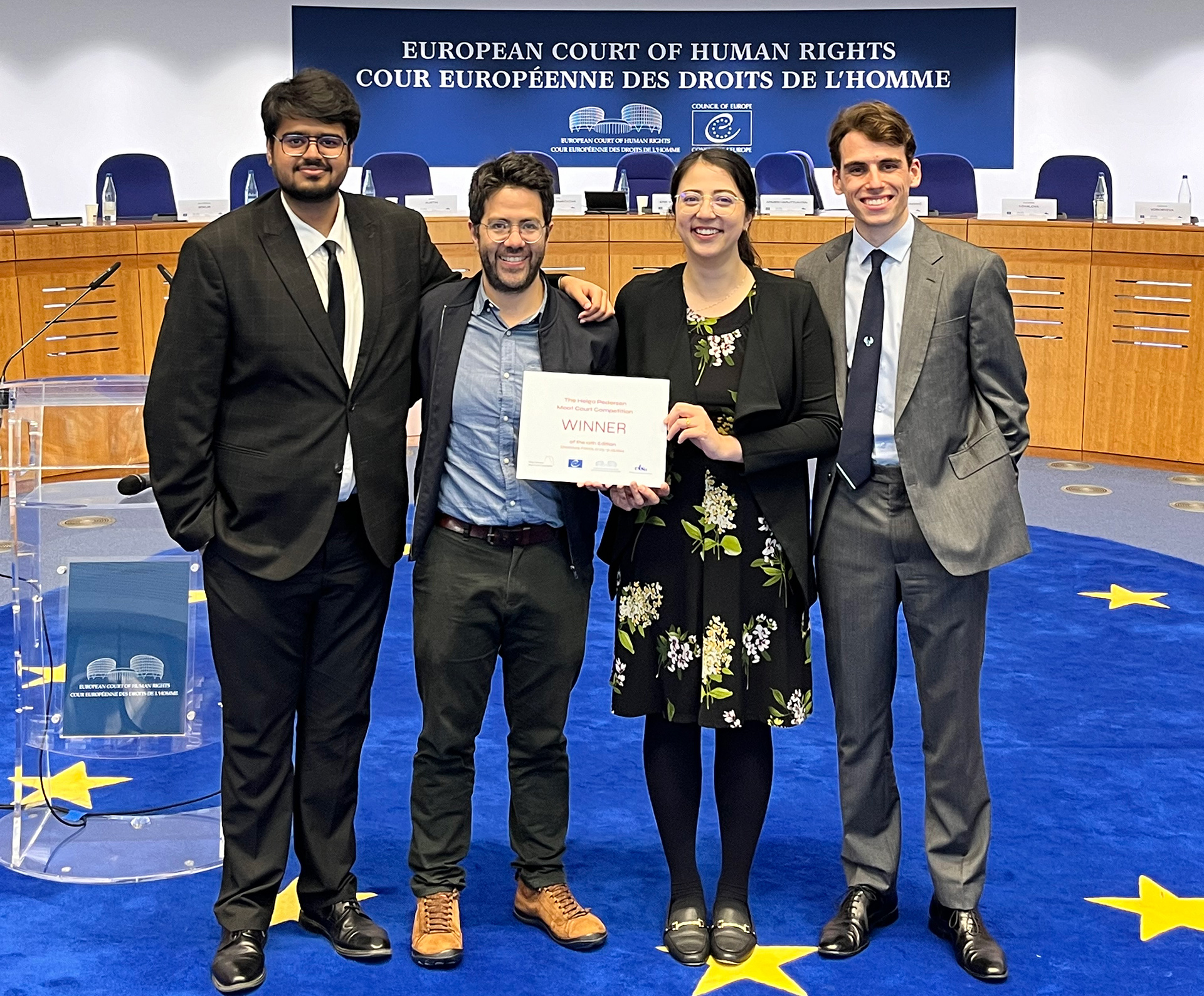 Four students stand with a winner certificate in the European Court of Human Rights
