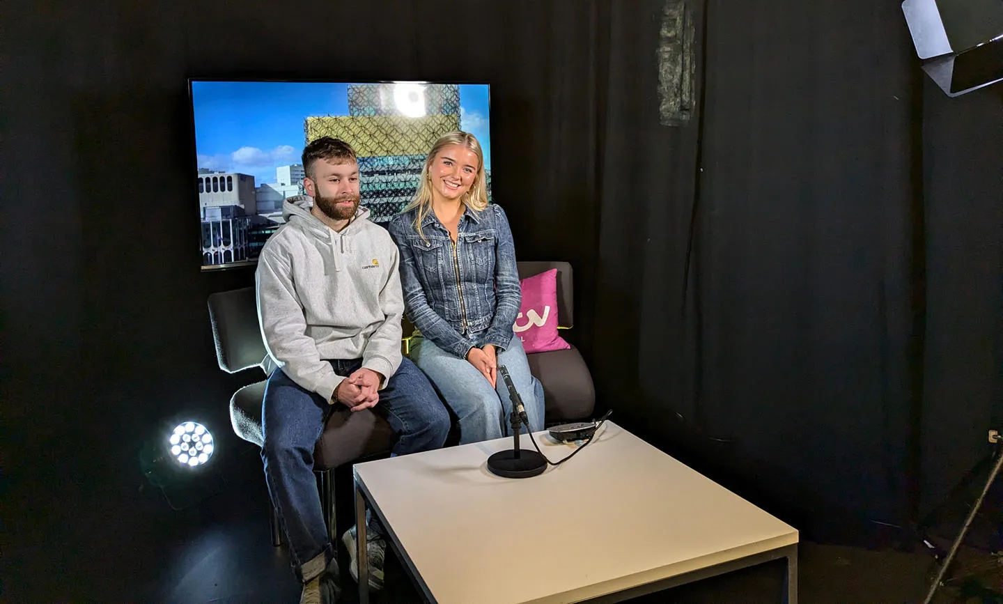 Students sit in a mock-up tv studio