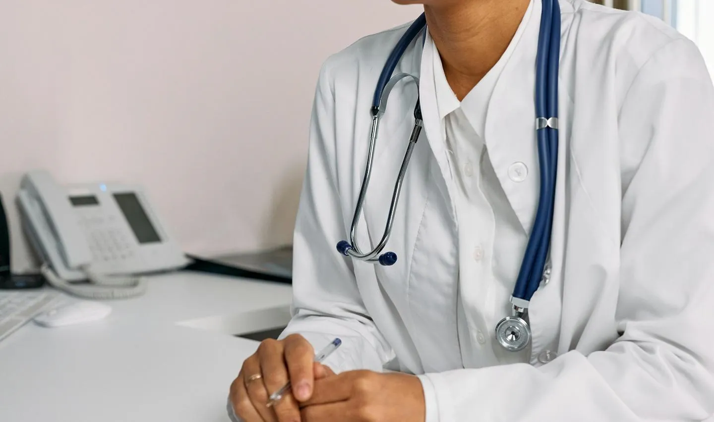 Close up of a GP sat at a desk during a consultation