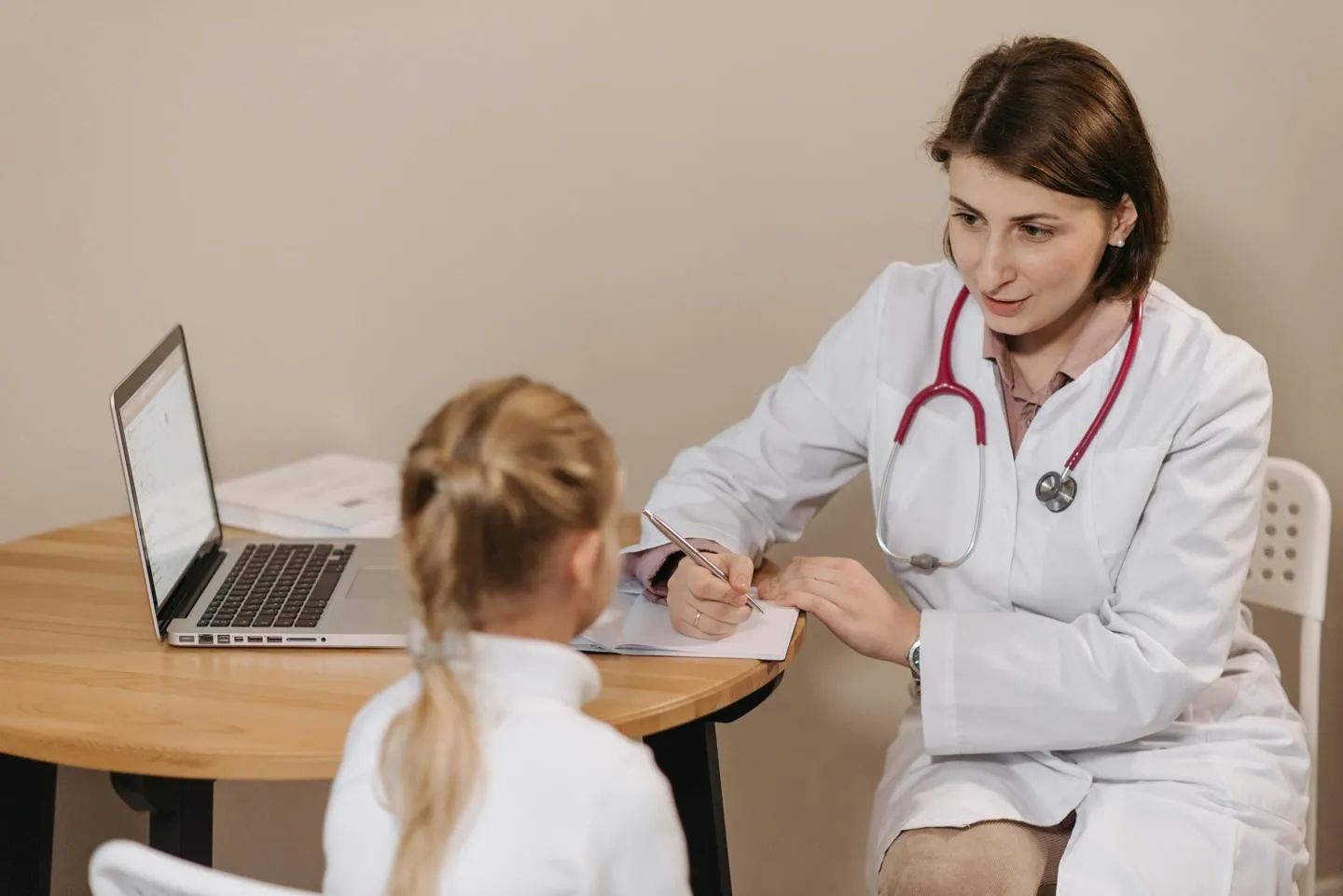 Doctor wearing white clinical coat talking to young girl
