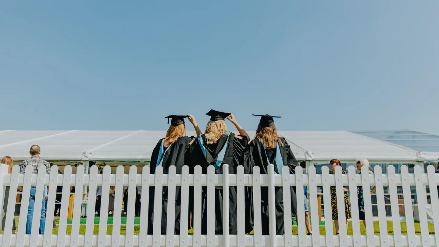 Three graduates on graduation day facing away from the camera