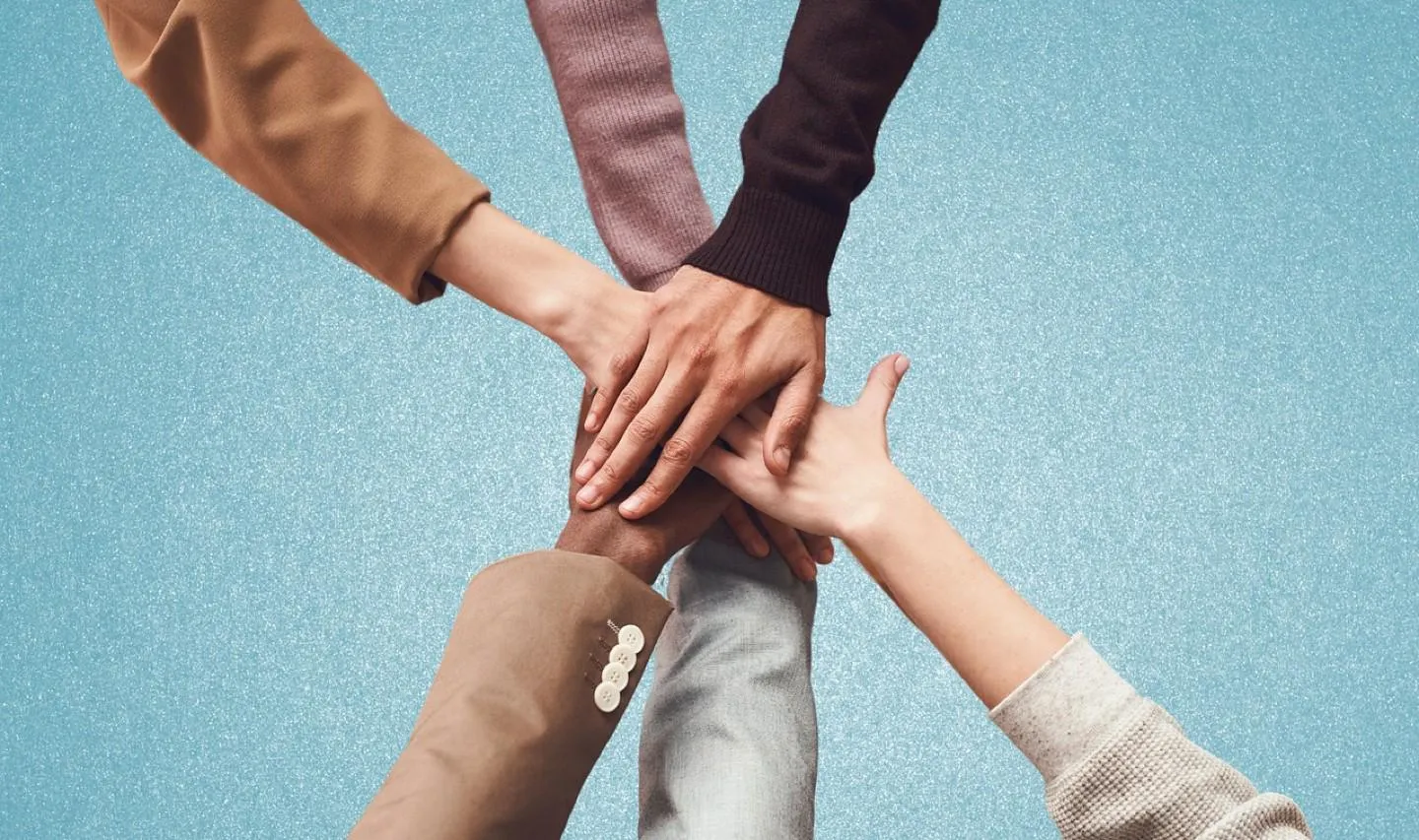 a diverse group of hands meeting in the centre of an image