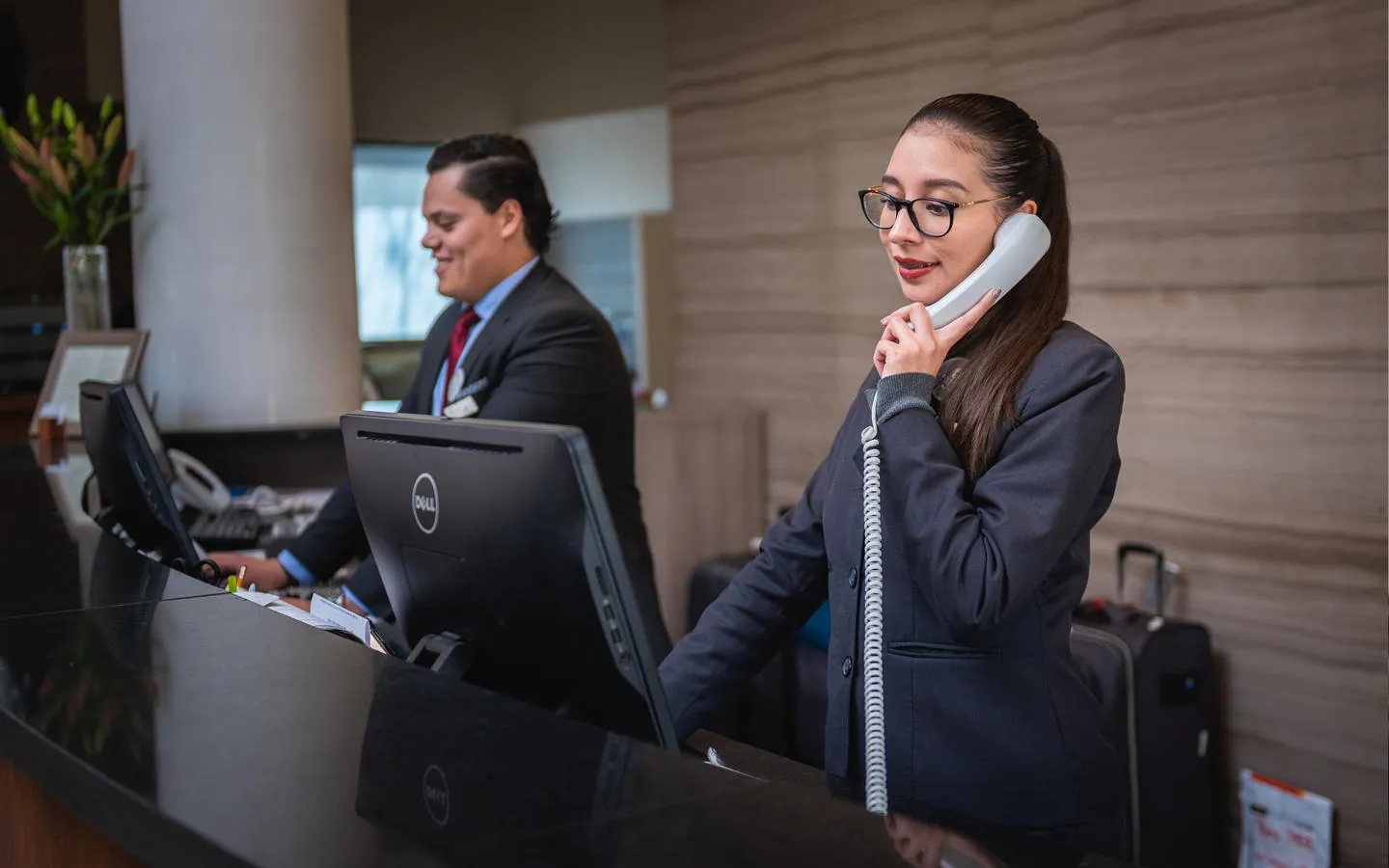 Male and female receptionists working on the front desk of a hotel