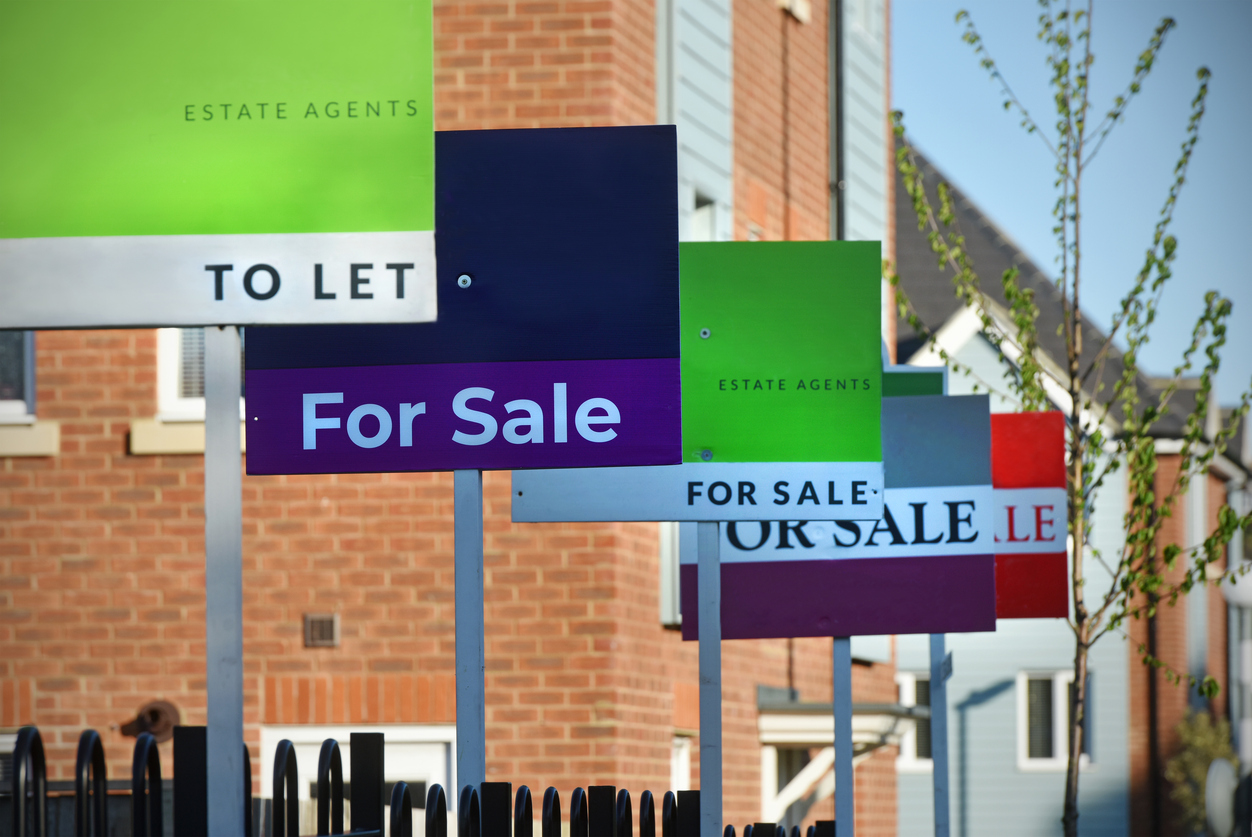 A row of estate agent signs 'for sale' and 'to let'