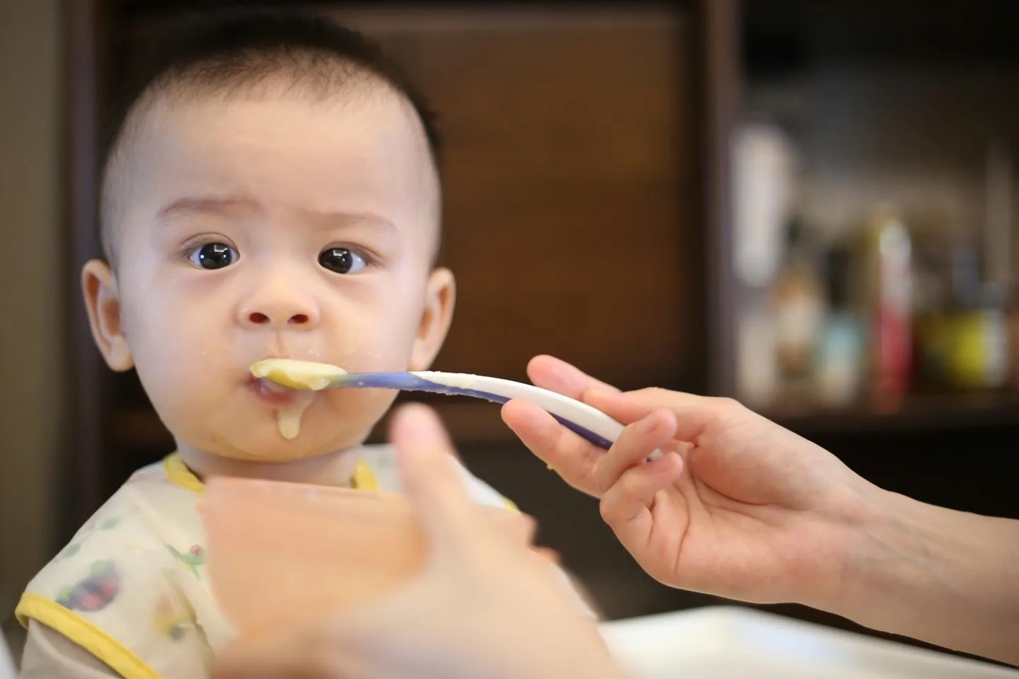 A baby being fed purée with a plastic spoon