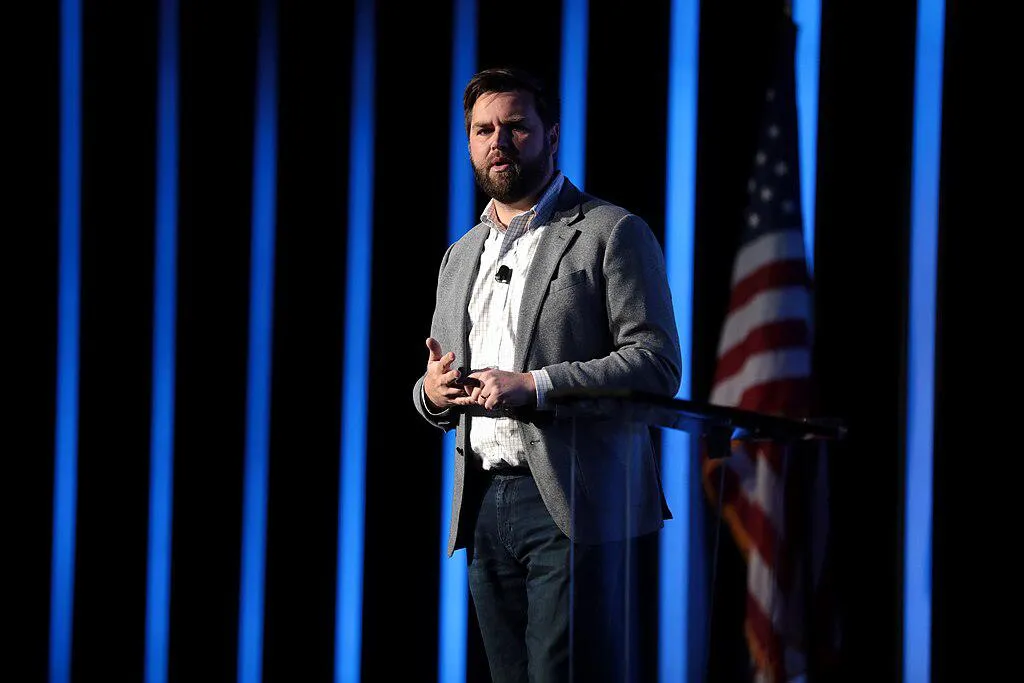 JD Vance giving a talk in front of an American flag.