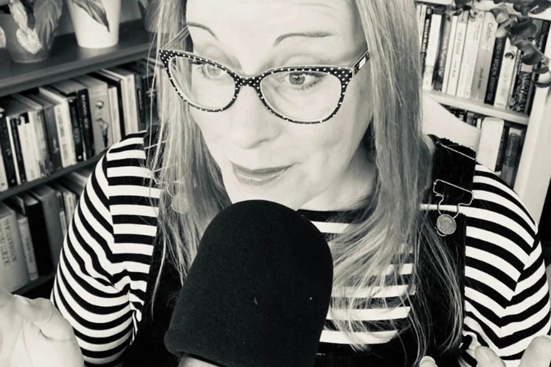 Portrait of Dr Joanna Bucknall at a microphone recording her podcast series.