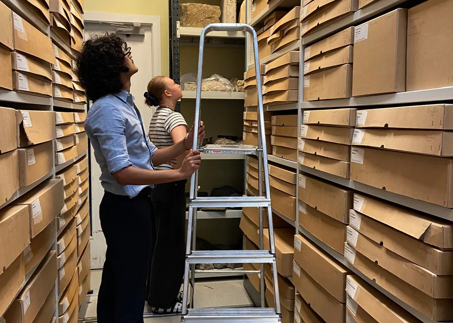 Two students stand in the Museum stores observing the vast amount of boxed material.