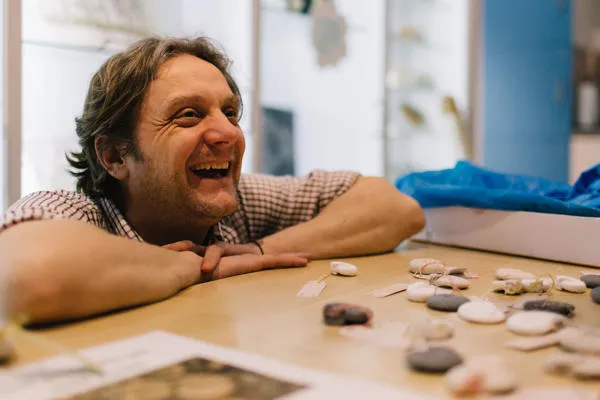 A man crouches at a table of fossils.